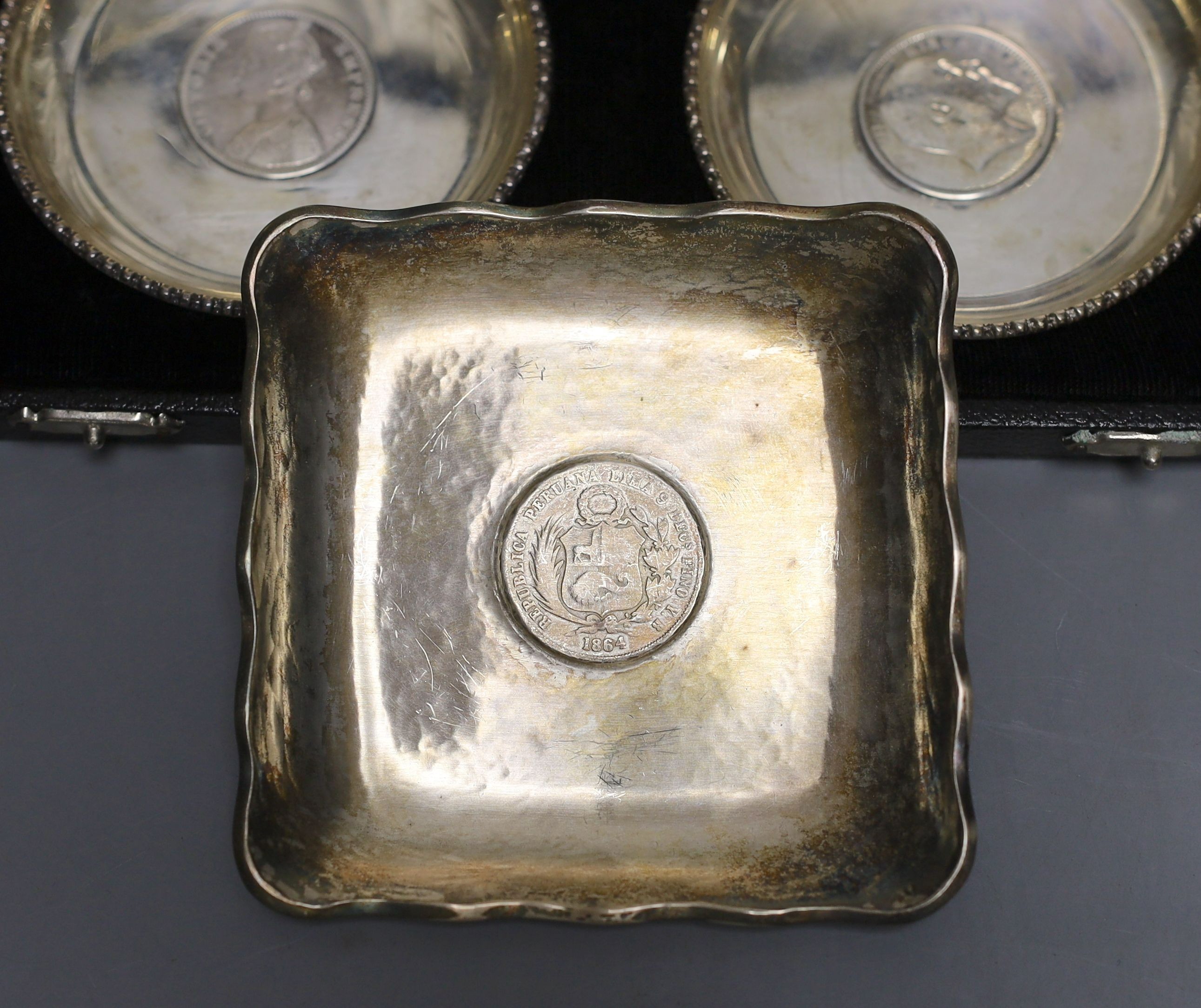 A cased pair of white metal inset coin small dishes and three other similar dishes.